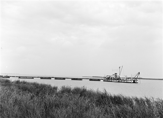 De dijk bij Stellendam wordt hersteld na de watersnoodramp van 1 februari 1953. Zand en water worden via een buis geperst naar de plek waar een nieuw dijklichaam wordt opgespoten.