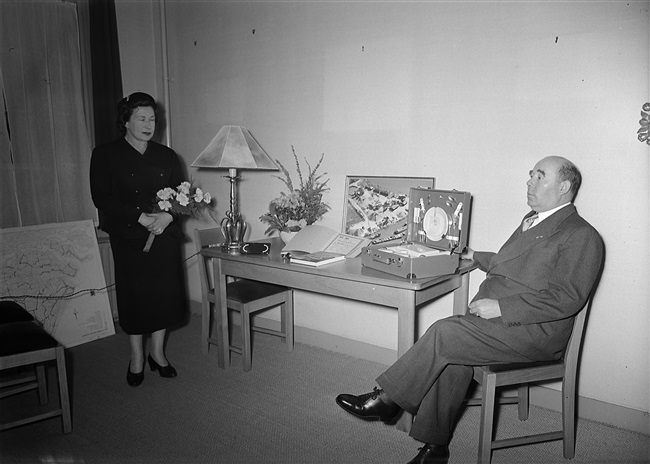 Het 25-jarig ambtsjubileum van ir. D.M. Mathlener, adjunct-directeur-hoofdingenieur van de Provinciale Waterstaat in Zuid-Holland. Ir. Mathlener en zijn vrouw poseren bij de jubileumgeschenken.