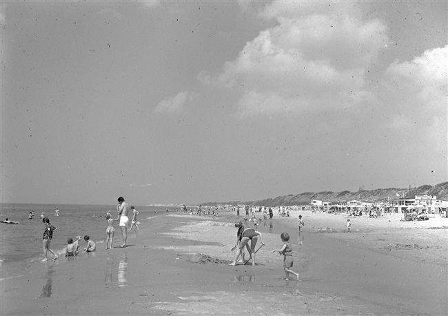 Zomerse drukte met dagjesmensen op het strand. De provincie Zuid-Holland maakt stranden beter bereikbaar door het aanleggen of verbeteren van wegen ernaartoe.