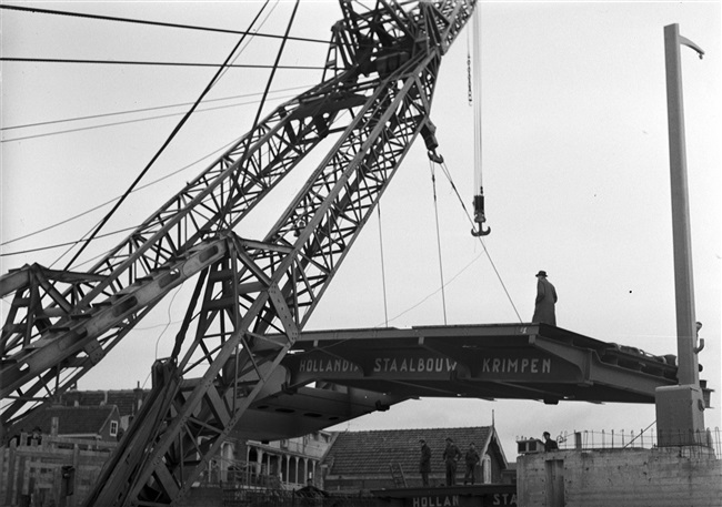 Een drijvende bok plaatst de bovenbouw van de Oude Tolbrug die wordt vernieuwd. De basculebrug over het Rijn-Schiekanaal komt tussen de Westvlietweg en de Fonteynenburghlaan.