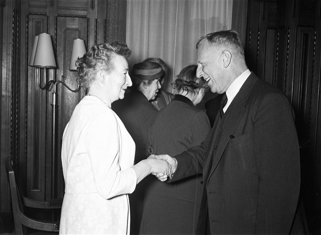Gedeputeerde mr. T.A. van Dijken schudt mevrouw Stegeman de hand bij haar ambtsjubileum en afscheid, aan het Korte Voorhout 1.