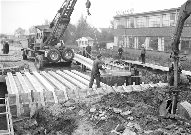 Aanleg van een weg op zandpalen (Abram van Rijckevorselweg) in het voormalige dorp Kralingse Veer. Rechts firma Bouman N.V.