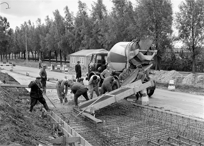 Een kruising in de Tiendweg wordt verbeterd. Uit een betonwagen wordt beton gestort in de wapening voor het wegdek.