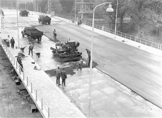 Asfaltafwerkers werken het asfalt af op het brugdek van de eerste St. Sebastiaansbrug. De basculebrug over het Rijn-Schiekanaal verbindt de oude binnenstad van Delft met de TU-wijk.