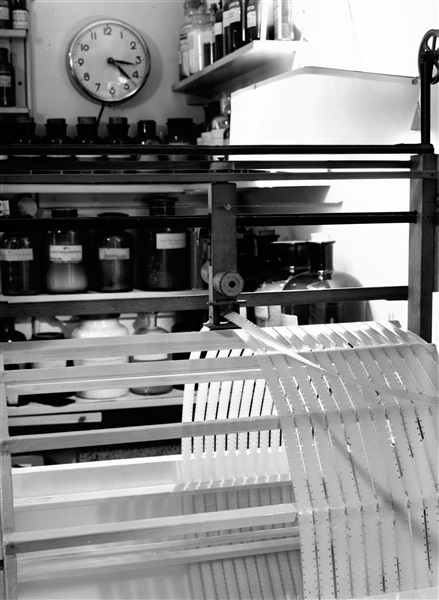 De Fotografische afdeling van de Provinciale Waterstaat in een pand aan de Riouwstraat. Dit apparaat plaatst een film op een ontwikkelmachine. De foto is gemaakt rond 1960.