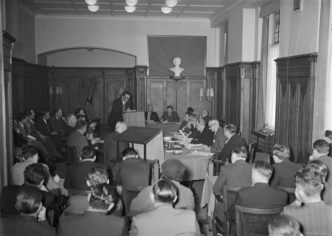 Openbare vergadering van de Gedeputeerde Staten in Den Haag. Het Haagsche Taxi vraagstuk wordt behandeld aan het Korte Voorhout 1. Rechts aan tafel zitten o.a. griffier mr. F.A. Helmstrijd en gedeputeerde mr. H. van Riel.