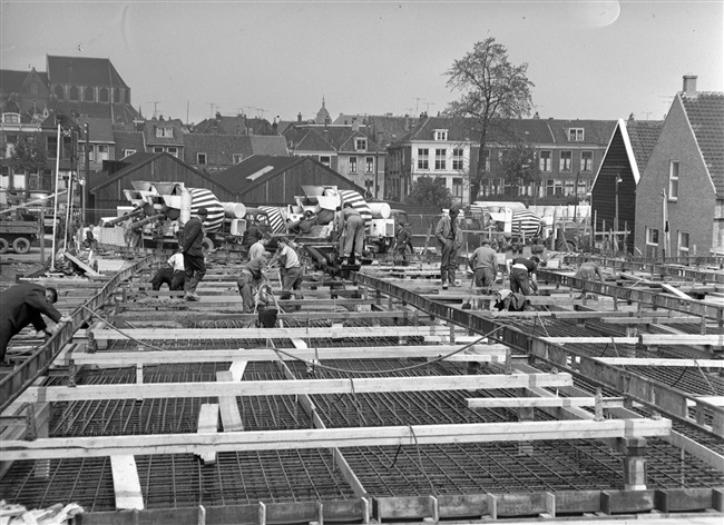 Betontimmermannen storten beton in de bekisting voor het noordelijke viaduct. Het viaduct is onderdeel van de eerste St. Sebastiaansbrug.