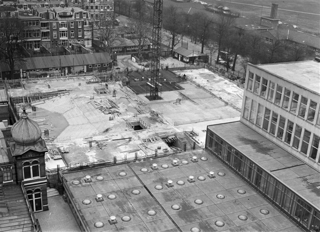 De vloeren van het hoofdgebouw (huidige gebouw C) worden gestort. In dit gedeelte van het provinciehuis komen o.a. de Statenzaal en de entreehal. Links op de achtergrond de lange keet van de aannemer en rechts de bouwkeet van de bouwdirectie en de tekenkamer.