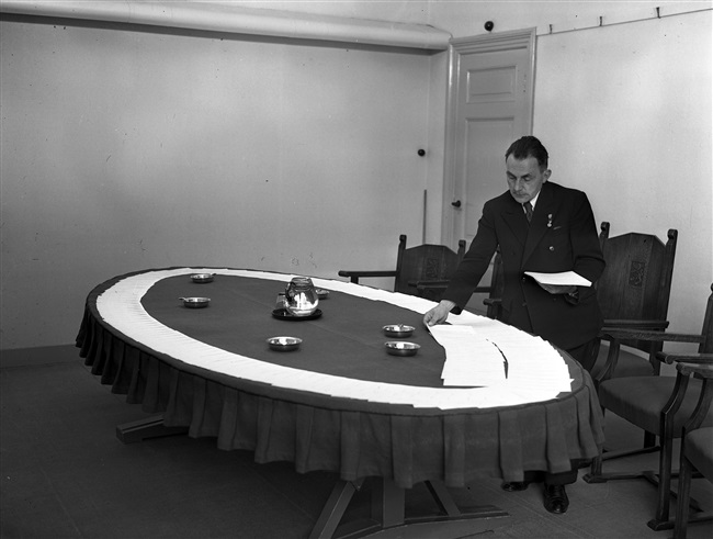 Een ambtenaar van de Provinciale Waterstaat legt documenten klaar in de vergaderzaal. De foto is waarschijnlijk gemaakt tussen 1950 en 1952.