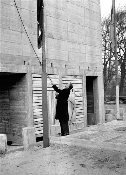 Bouw van het provinciehuis aan de Koningskade. Jan Klaasesz, commissaris van de Koningin, hijst de nationale driekleur: het hoogste punt van het gebouw, 51 meter boven de begane grond, is bereikt.