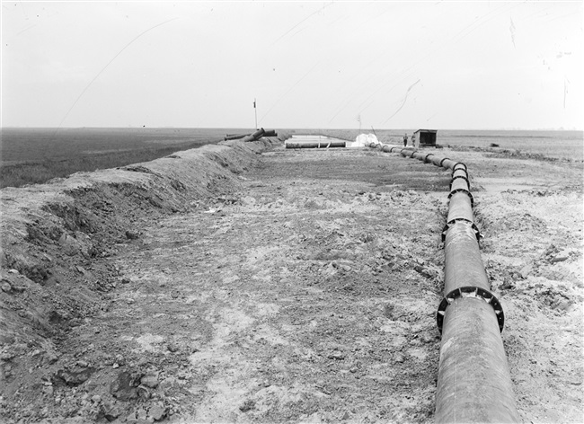 De dijk bij Stellendam wordt hersteld na de watersnoodramp van 1 februari 1953. Zand en water worden via een buis geperst naar de plek waar een nieuw dijklichaam wordt opgespoten.