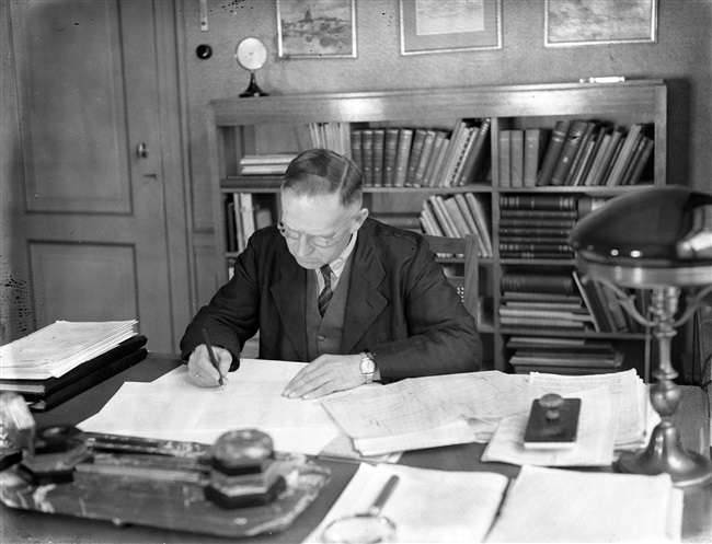 Ir. Lambertus Tjerk van der Wal in zijn werkkamer. Van der Wal was directeur-hoofdingenieur van de Provinciale Waterstaat in Zuid-Holland. Vanaf 1941 was hij ook directeur van de Provinciale Planologische Dienst. De foto is gemaakt tussen 1930 en 1950.