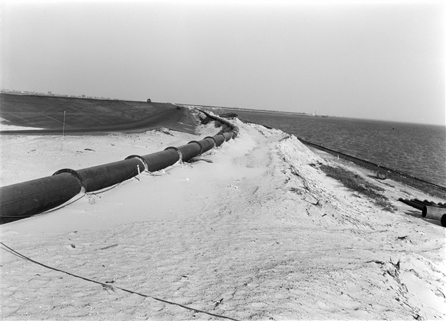 De dijk bij de Hoek van Sint Jacob op Goeree-Overflakkee wordt hersteld na de watersnoodramp van 1 februari 1953. Zand en water worden via een buis geperst naar de plek waar een nieuw dijklichaam wordt opgespoten.