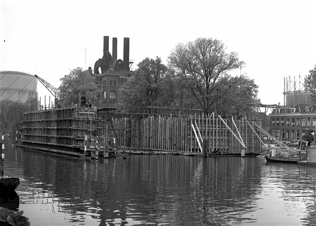 Bekistingen van de middenpijler en het landhoofd van de eerste St. Sebastiaansbrug, over het Rijn-Schiekanaal. De basculebrug verbindt de oude binnenstad van Delft met de TU-wijk. Op de achtergrond de gasfabriek, die later is gesloopt.
