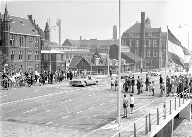 Opening van de eerste St. Sebastiaansbrug over het Rijn-Schiekanaal. De basculebrug verbindt de oude binnenstad van Delft met de TU-wijk. Op de achtergrond het voormalige laboratorium van de Afdeling Physica en Electrotechniek van de Polytechnische School.