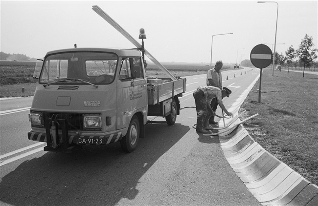 Kantonniers werken met een verfspuit de signalering bij