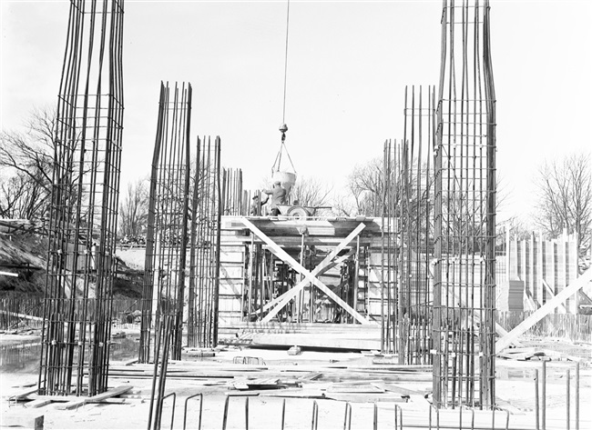 De wapening voor de betonkolommen van het in aanbouw zijnde provinciehuis. Op de achtergrond storten betonstorters de betonkolommen.