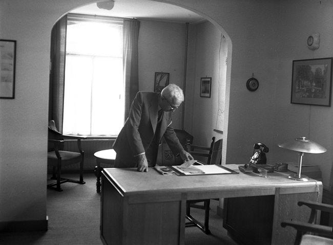 Een ambtenaar van Provinciale Waterstaat in zijn kantoor. De foto is waarschijnlijk gemaakt tussen 1950 en 1952.