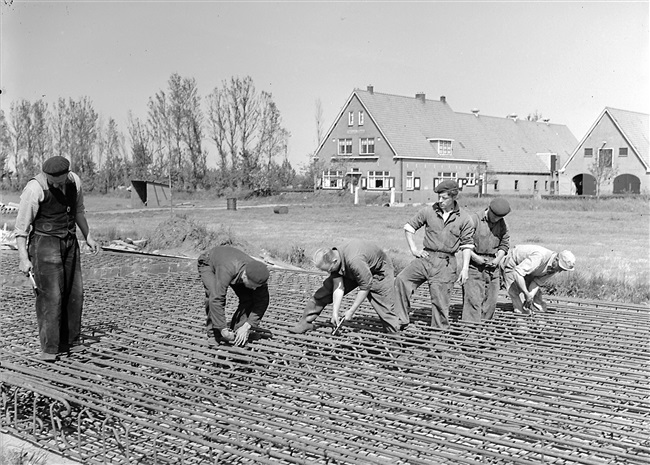 Aanleg van de weg op palen tussen Boskoop en Alphen aan den Rijn. IJzervlechters vlechten het wapeningsstaal voor de platen.