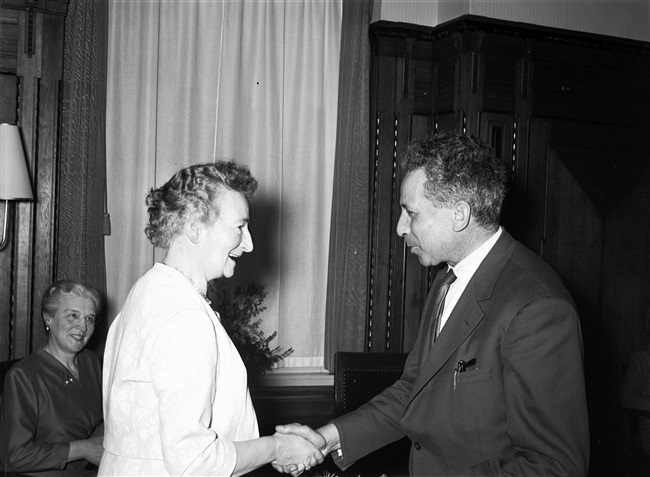 Gedeputeerde J.P. van Praag schudt mevrouw Stegeman de hand bij haar ambtsjubileum en afscheid, aan het Korte Voorhout 1.