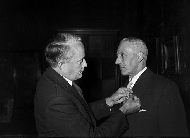 Ambtsjubileum van de heer Langeveld, vermoedelijk opzichter 3e klasse van de Provinciale Waterstaat. De commissaris van de Koningin Jan Klaasesz speldt hem een Koninklijke onderscheiding op.