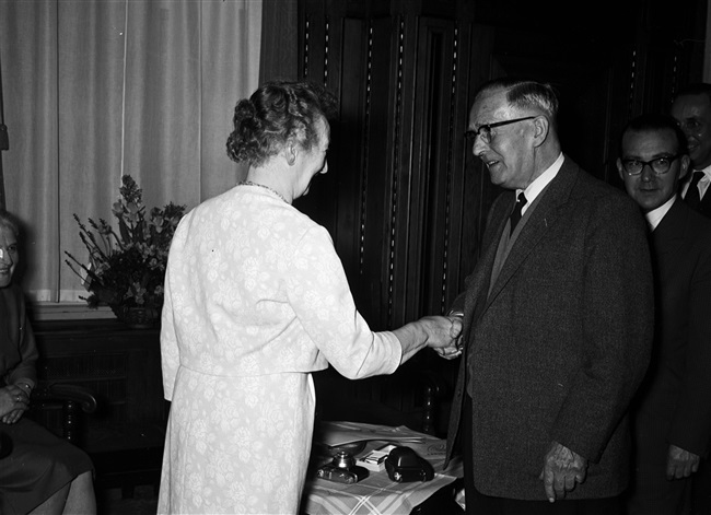 Ir. L.T. van der Wal schudt mevrouw Stegeman de hand bij haar ambtsjubileum en afscheid, Korte Voorhout 1.
