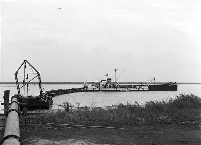 De dijk bij Stellendam wordt hersteld na de watersnoodramp van 1 februari 1953. Zand en water worden via een buis geperst naar de plek waar een nieuw dijklichaam wordt opgespoten.