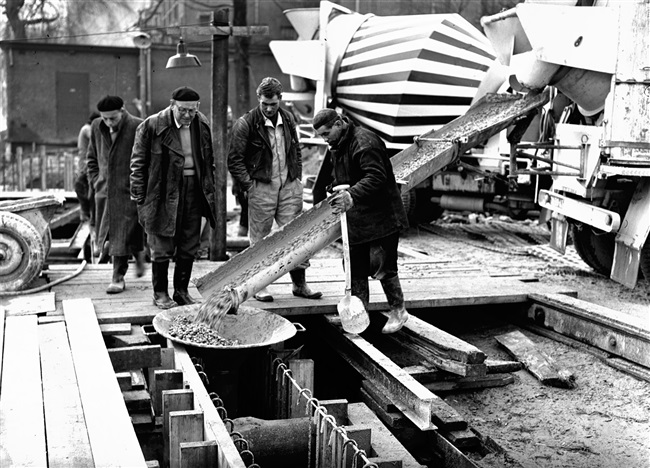 Een betonstorter stort beton in de bekistingen voor de keldervloer en de wanden van de eerste St. Sebastiaansbrug.