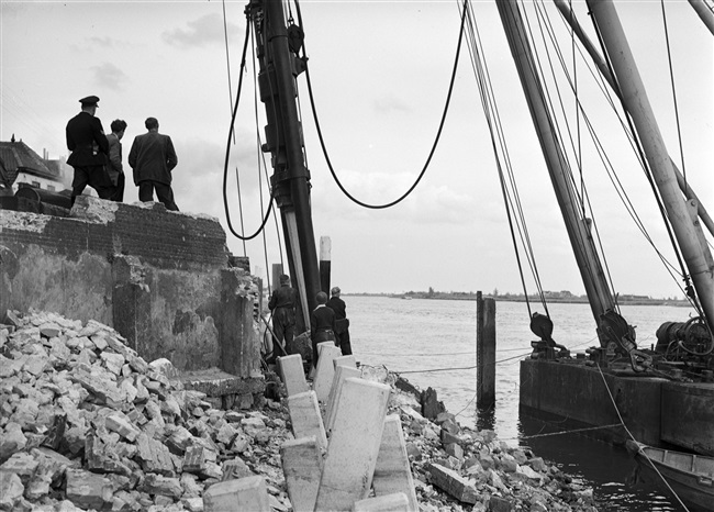 Palen heien voor muur aan Voorstraat in Lekkerkerk, 1957