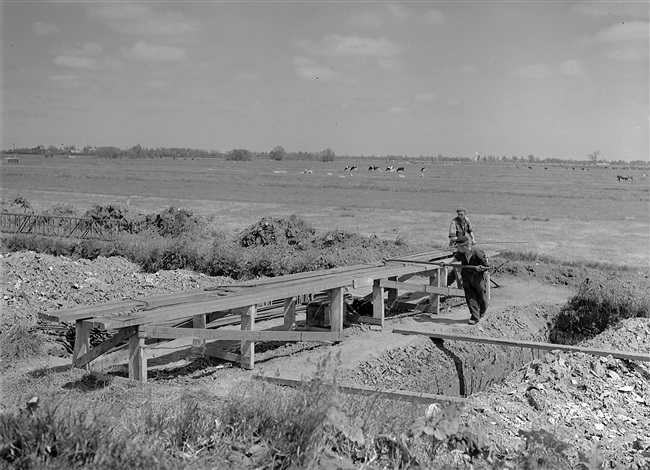 Aanleg van de weg op palen tussen Boskoop en Alphen aan den Rijn. IJzervlechters buigen het ijzer voor de wapening van de dwarsbalken. Op de dwarsbalken komt later het wegdek te rusten.