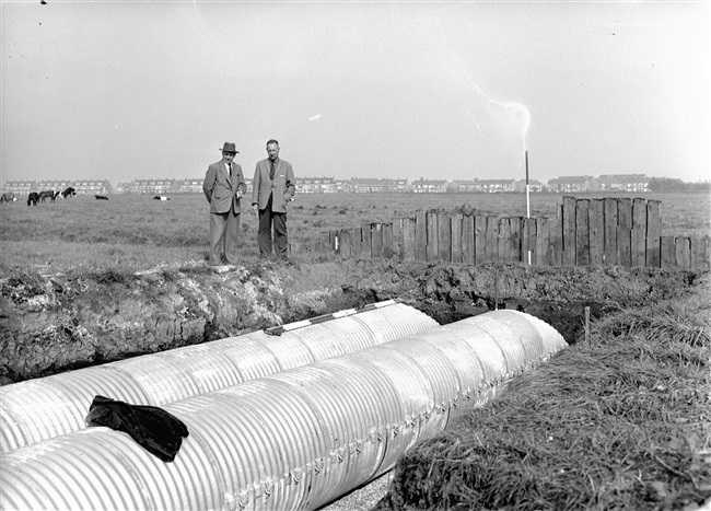 Bij een dijkaanleg worden duikers geplaatst van Aramko-buizen, voor een goede afwatering van de polders.